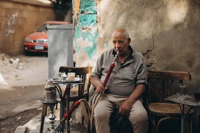 Homme fumant le narguilé dans une ruelle du Caire en Égypte